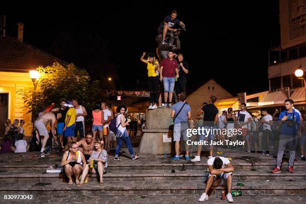 Revellers gather around the Guca trumpeter statue during the Guca Trumpet Festival on August 10, 2017 in Guca, Serbia. Thousands of revellers attend...