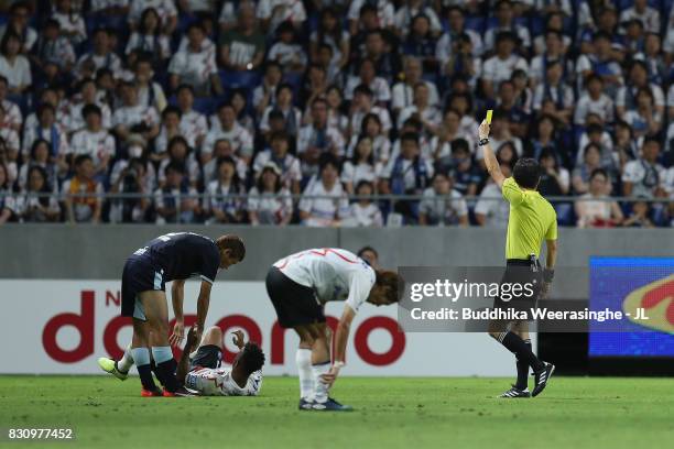 Kentaro Oi of Jubilo Iwata is shown a yellow card by referee Hiroyuki Kimura during the J.League J1 match between Gamba Osaka and Jubilo Iwata at...