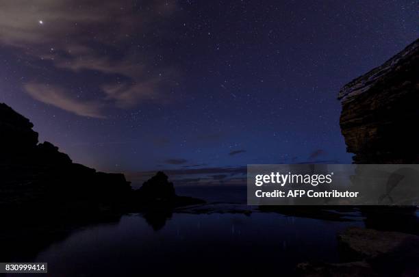 This picture taken on August 12, 2017 shows a Perseid meteor along the Milky Way illuminating the dark sky near Comillas, Cantabria community,...