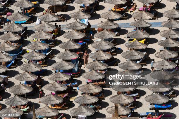 People sunbathe on Llaman Beach, near the city of Himare, on August 13, 2017. The hot weather conditions of the last days in Albania have seen...