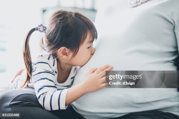 cute little girl touching and kissing to pregnant mother's belly with joy - belly kissing stock pictures, royalty-free photos & images