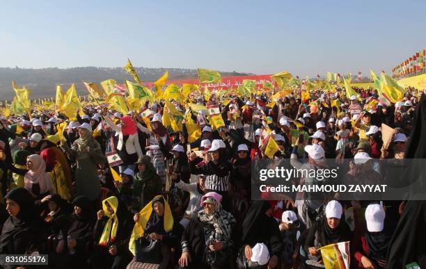 Supporters of the Lebanese Shiite movement Hezbollah fly the group's flag during a speech by the head of the movement to mark the 11th anniversary of...
