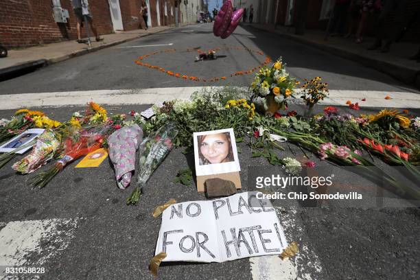 Flowers surround a photo of 32-year-old Heather Heyer, who was killed when a car plowed into a crowd of people protesting against the white...