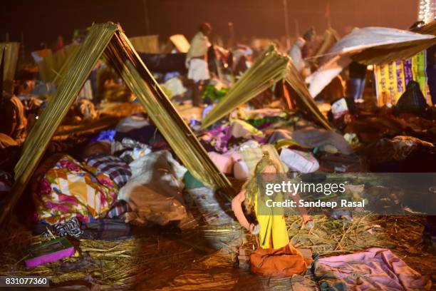 idol of sadhu stand still as pilgrims sleep in the night in makeshift tents during ganga sagar fair - ganga sagar stock pictures, royalty-free photos & images