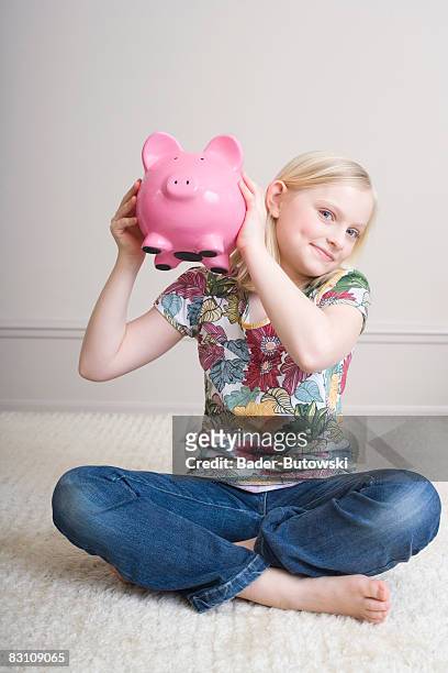 girl (8-9) holding piggy bank, portrait - blonde girl piggy bank stock-fotos und bilder