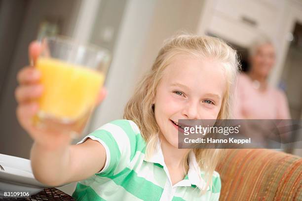 girl (8-9) holding glass, grandmother in background - orange juice glass white background stock pictures, royalty-free photos & images