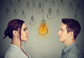 Cognitive skills ability concept, male vs female. Man and woman looking at bright light bulb isolated on gray wall background