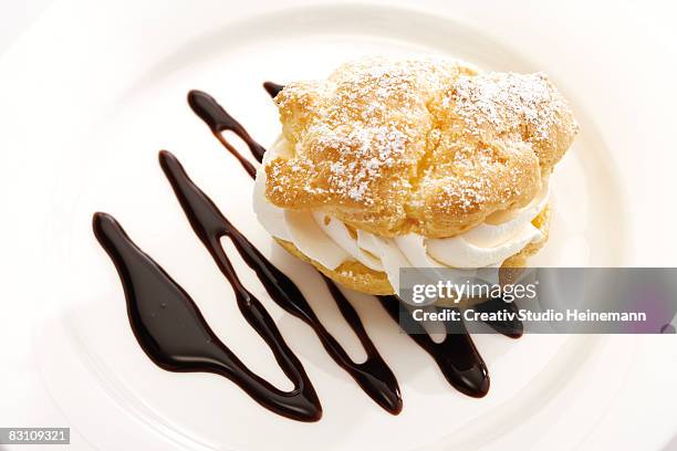 cream puff with chocolate sauce on plate - chocolate sauce stock pictures, royalty-free photos & images