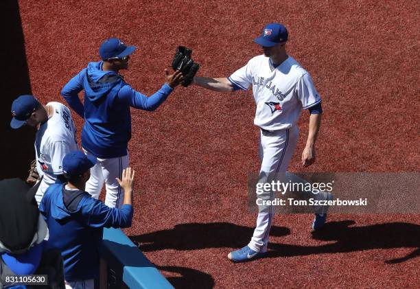 Happ of the Toronto Blue Jays is congratulated by Marcus Stroman as he walks to his dugout after getting the last out of the sixth inning during MLB...