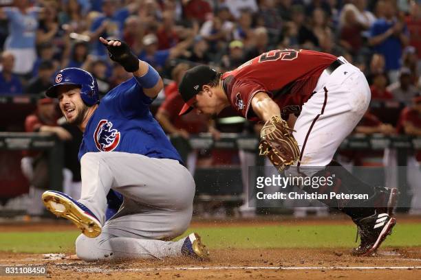 Kris Bryant of the Chicago Cubs safely slides into home plate to score a run past starting pitcher Zack Godley of the Arizona Diamondbacks during the...