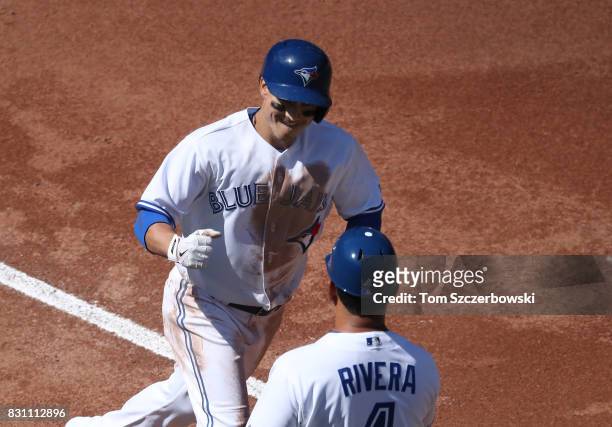 Darwin Barney of the Toronto Blue Jays is congratulated by third base coach Luis Rivera as he circles the bases after hitting a solo home run in the...