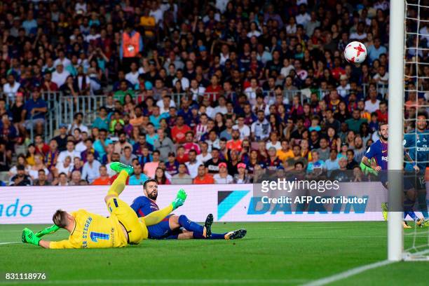 Barcelona's defender Gerard Pique eyes the ball as he scores an own goal during the first leg of the Spanish Supercup football match between FC...