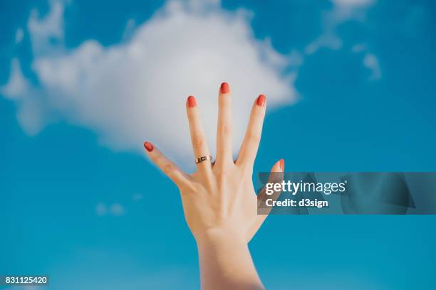 woman's hand against blue sky and white clouds - red nail polish stock pictures, royalty-free photos & images