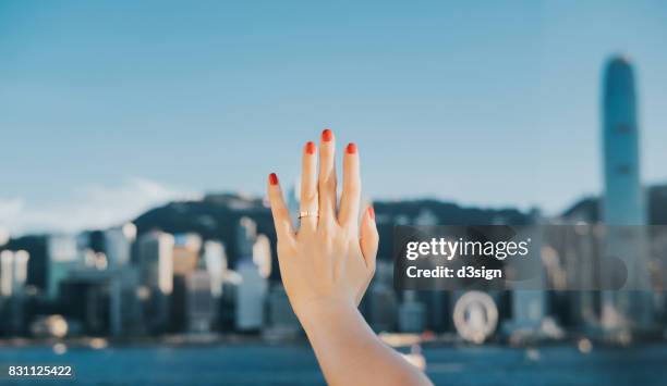 woman's hand against iconic skyline of hong kong victoria harbour - リング ストックフォトと画像