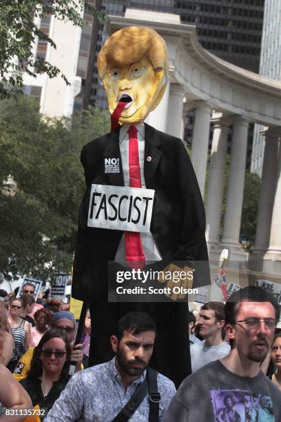 Demonstrators protesting the alt-right movement and mourning the victims of yesterdays rally in Charlottesville, Virginia carry a puppet of President...