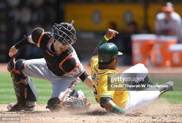 Khris Davis of the Oakland Athletics scores sliding past the tag of Caleb Joseph of the Baltimore Orioles in the bottom of the fourth inning at...