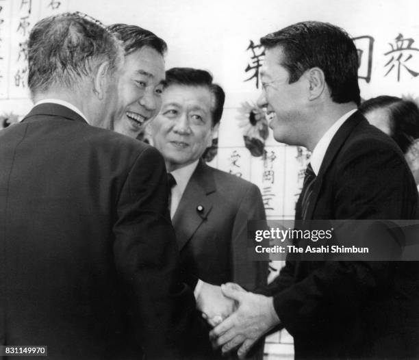 Japan Renewal Party President Tsutomu Hata and executive Ichiro Ozawa shake hands as the vote counting of the general election continues on July 18,...