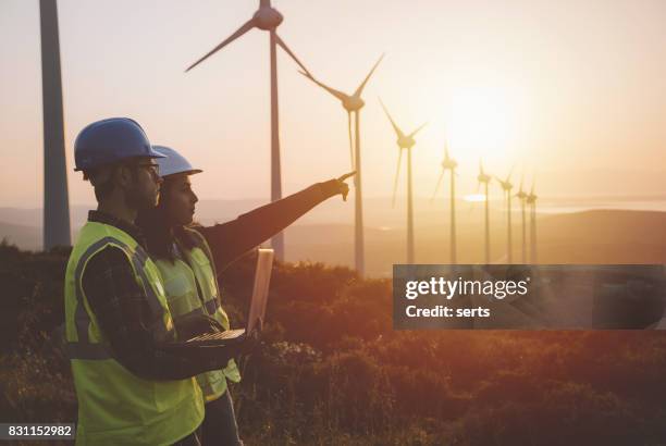 equipe de manutenção jovem engenheiro trabalhando na fazenda de turbina de vento ao pôr do sol - engineering - fotografias e filmes do acervo