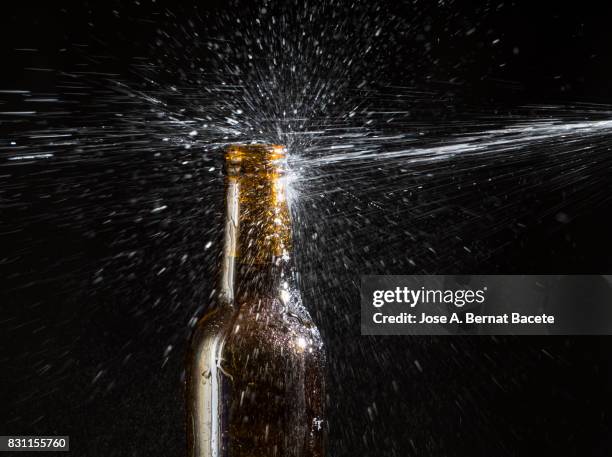 bottle of beer with the glass esmerilado with drops of water and a steam cloud frozen on a black background - beer splash stock pictures, royalty-free photos & images