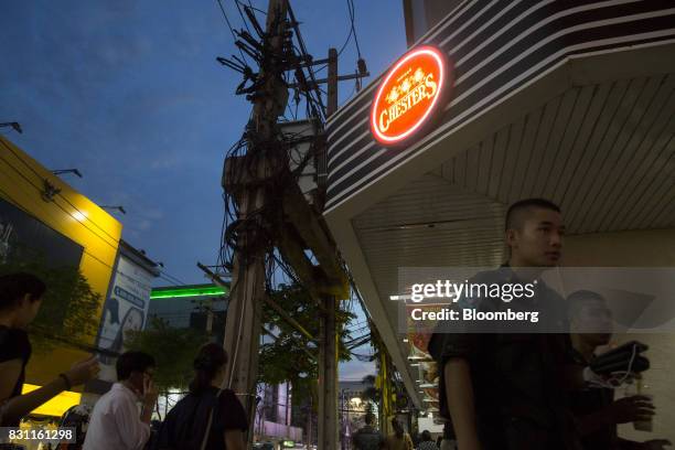 Pedestrians walk past an illuminated sign for a Chester's Grill restaurant in Bangkok, Thailand, on Friday, Aug. 11, 2017. Thai Beverage, the spirits...