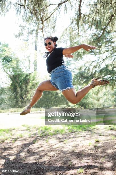 woman jumping for joy in at elegant manner at the park - ladies shorts stockfoto's en -beelden