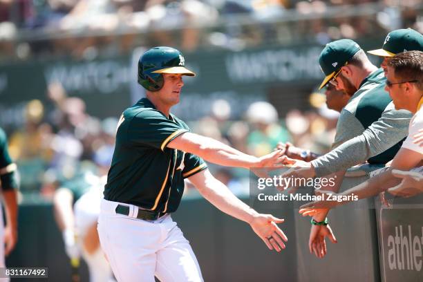 Jaycob Brugman of the Oakland Athletics is congratulated at the dugout during the game against the Tampa Bay Rays at the Oakland Alameda Coliseum on...