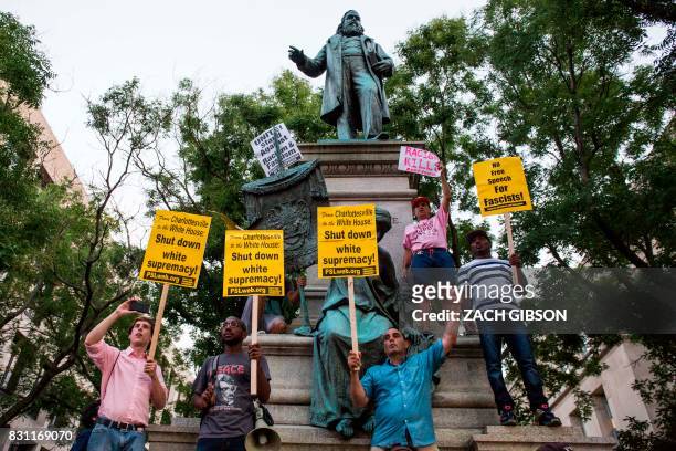 Demonstrators hold signs while standing in front of the statue of Confederate General Albert Pike on August 13, 2017 in Washington, DC, the only...