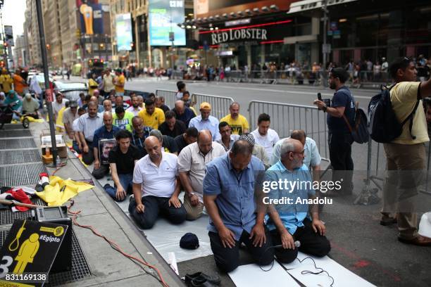 People perform a prayer during a protest marking the fourth anniversary of Rabaa El Adaweya massacre in Times Square of Manhattan borough of New...