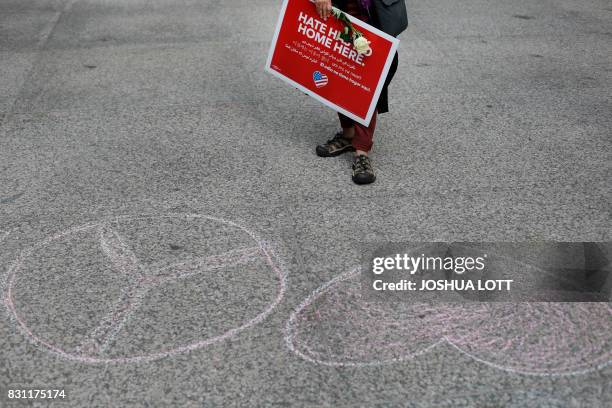 Woman holds a flower and sign during a vigil August 13, 2017 in Chicago, Illinois for the victim in the previous day's violent clashes in...