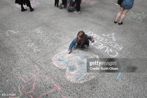 Seven-year-old Julia Manthei chalks "Love Not Hate" onto the plaza before the start of an event to protest against the alt-right movement and to...