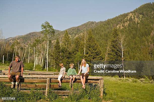 family in nature sitting on fence on camp trip. - ketchum idaho stock pictures, royalty-free photos & images