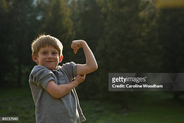 boy flexes his muscles in wilderness on camp trip. - kids proud bildbanksfoton och bilder