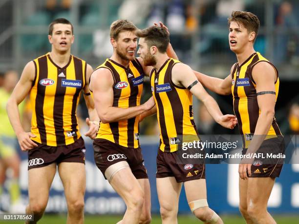 Teia Miles of the Hawks celebrates a goal with teammates L-R Ryan Burton, Ryan Schoenmakers and Daniel Howe during the 2017 AFL round 21 match...
