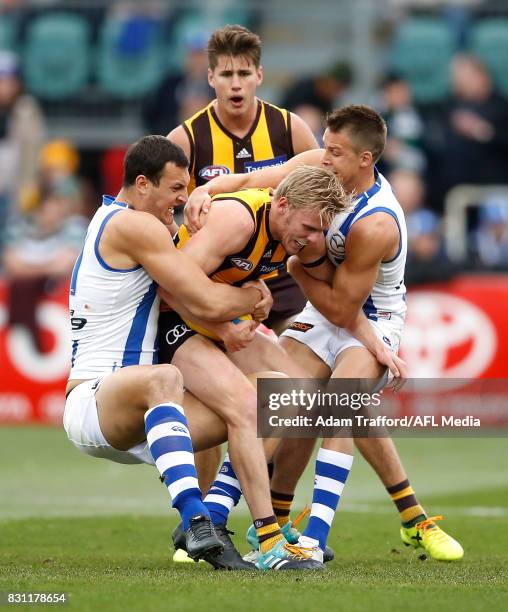 Will Langford of the Hawks is tackled by Braydon Preuss and Andrew Swallow of the Kangaroos during the 2017 AFL round 21 match between the Hawthorn...
