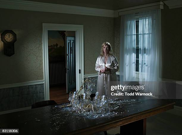 woman looking at fallen chandelier - creepy house at night stock-fotos und bilder