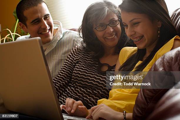 famiglia ridere mentre usa un computer portatile - girl looking at computer foto e immagini stock