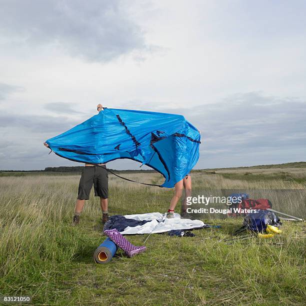 young couple setting up tent. - tent foto e immagini stock