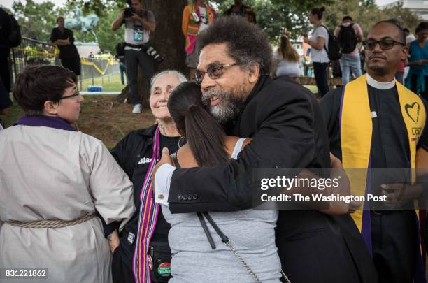 Cornell West hugs counter protestors outside Emancipation Park during the Unite the Right Rally, while the self-proclaimed group, The Militia, stands...