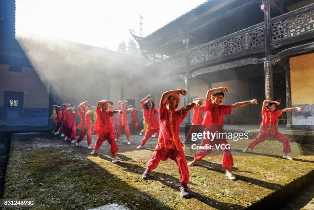 Children from a Shaolin martial art institute practise kung fu at a village in Suichuan County on August 13, 2017 in Ji'an, Jiangxi Province of China.