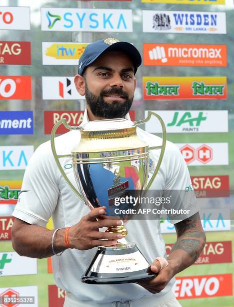 Indian cricket captain Virat Kohli gestures as he holds the trophy after victory in the third day of the third and final Test match between Sri Lanka...