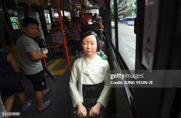 Boy looks at a statue of a teenage girl symbolizing former "comfort women" who served as sex slaves for Japanese soldiers during World War II, placed...