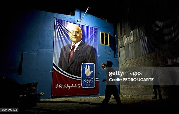 Man walks next to a poster of Maldivian president and Dhivehi Rahyithunge Party's presidential candidate Maumoon Abdul Gayoom in Male on October 4,...