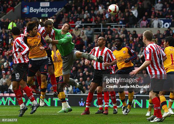 Cesc Fabregas of Arsenal scores a goal despite the challenge of George McCartney and Craig Gordon of Sunderland during the Barclays Premier League...