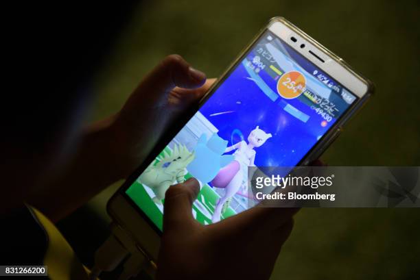 Player displays a Mewtwo character on their smartphone while playing Nintendo Co.'s Pokemon Go augmented-reality game, developed by Niantic Inc.,...