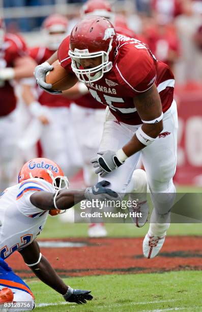 Williams of the Arkansas Razorbacks is tripped up by a defender during a game against the Florida Gators at Donald W. Reynolds Stadium on October 4,...