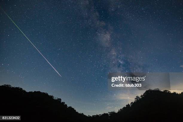 una meteora spara attraverso il cielo notturno lasciando una scia di luce attraverso la via lattea - stelle cadenti foto e immagini stock