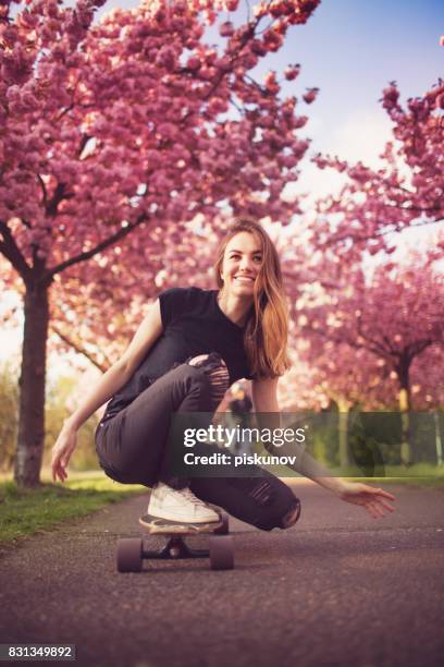 jeune femme avec longboard en allée de cerisiers en fleurs - adult girl single park photos et images de collection