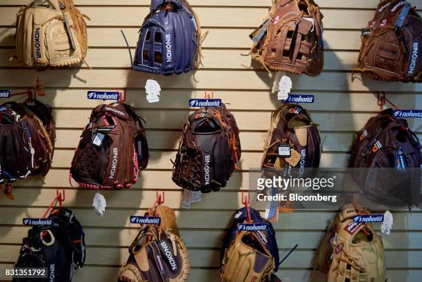 Nokona baseball and softball gloves hang on display for sale inside the store at the company's manufacturing facility in Nocona, Texas, U.S., on...