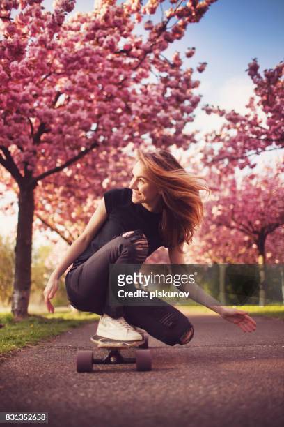 young woman with longboard in cherry blossom alley - piskunov imagens e fotografias de stock
