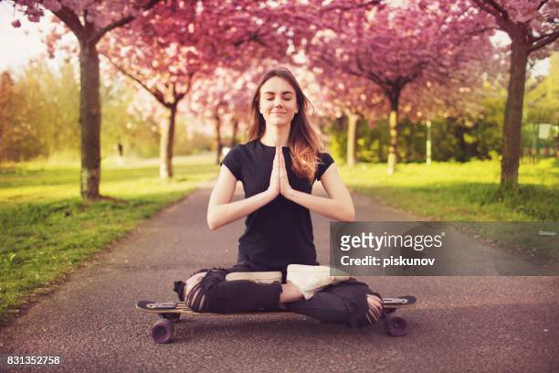 young woman with longboard in cherry blossom alley - yoga teen stock pictures, royalty-free photos & images